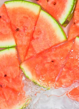 Close up view of the red melon slices in lemonade background. Texture of cooling sweet summer's drink with macro bubbles on the glass wall. Flat design.