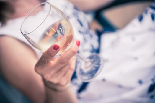 Beautiful young girl with blond hair holds a glass of wine and smiles, holidays