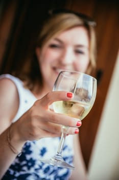 Beautiful young girl with blond hair holds a glass of wine and smiles, holidays