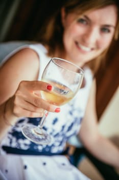 Beautiful young girl with blond hair holds a glass of wine and smiles, holidays