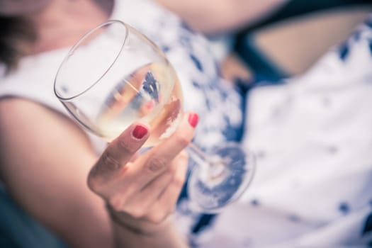 Beautiful young girl with blond hair holds a glass of wine and smiles, holidays