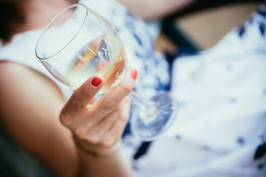 Beautiful young girl with blond hair holds a glass of wine and smiles, holidays