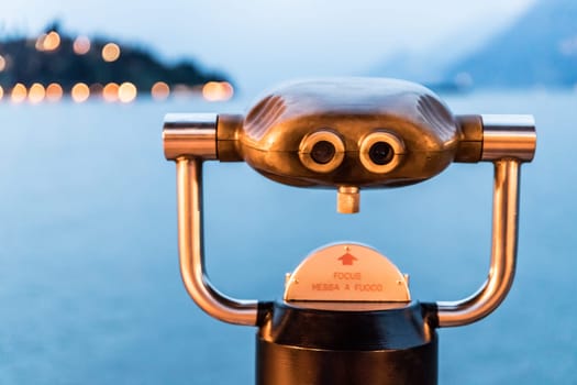 Tourist binoculars on the lake Lago di Garda, evening scene with water and mountains