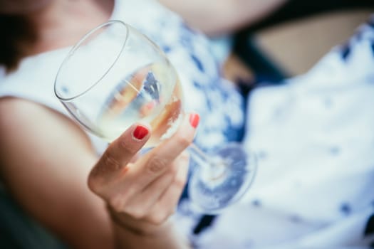 Beautiful young girl with blond hair holds a glass of wine and smiles, holidays