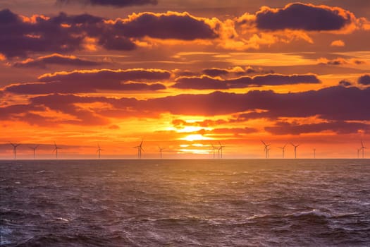 Sunrise at decarbonization industry windmills business for regenerative energies. Clean energy renewables preventing climate change.