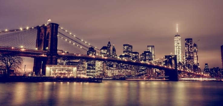 Brooklyn bridge and New York City Manhattan downtown skyline at dusk with skyscrapers illuminated over East River panorama. Copy space.
