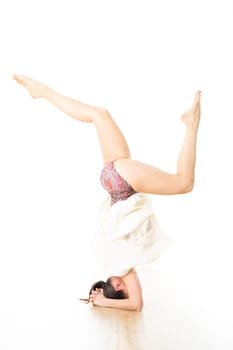Portrait of beautiful elegant slim active sporty young woman performing standing on head yoga pose in yoga studio. Healthy active lifestyle.