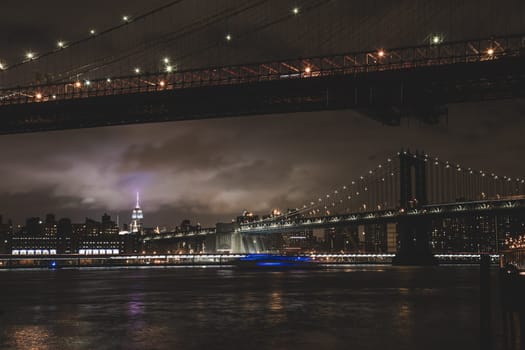Manhattan bridge and New York City downtown skyline at dusk with skyscrapers illuminated over East River panorama. Copy space.