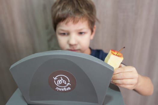 Child boy throwing apple core to waste bin for organic at home. Education about Waste Segregation concept
