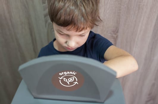 Child boy throwing prganic item to waste bin for orgnic at home. Education about waste segregation concept