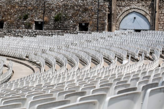 The empty auditorium with gray plastic chairs in an ancient amphitheater