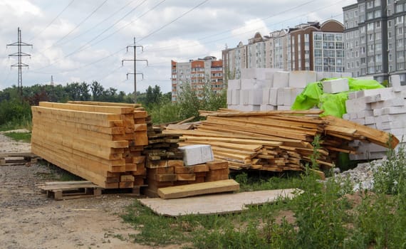 Stack of many wooden planks on a construction site, building material background. Renovation, roof overlap, construction and home concept. Wooden bars. Construction Materials