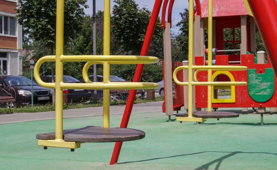 Closed modern playground. Security and protection measures against COVID-19 in the city park. Baby empty yellow metal swing in the park without people. The concept of childhood is over