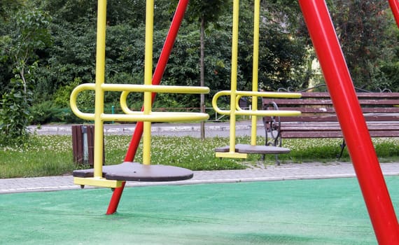 Closed modern playground. Security and protection measures against COVID-19 in the city park. Baby empty yellow metal swing in the park without people. The concept of childhood is over