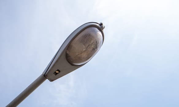 Street lamp close up. Big street lights at a big highway interchange. Close-up. Modern street lamp. Electric old lamp of street lighting on the background of blue sky and clouds during the day