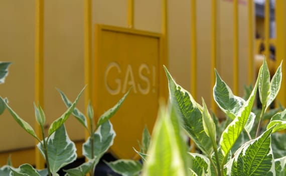 Warning on a metal cage with gas equipment for the public. Attention gas pipe. The inscription in English GAZ. A yellow warning sign for a medium pressure gas pipeline on a surface installation