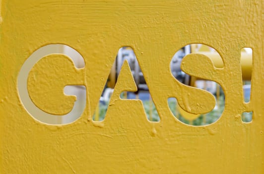 Warning on a metal cage with gas equipment for the public. Attention gas pipe. The inscription in English GAZ. A yellow warning sign for a medium pressure gas pipeline on a surface installation