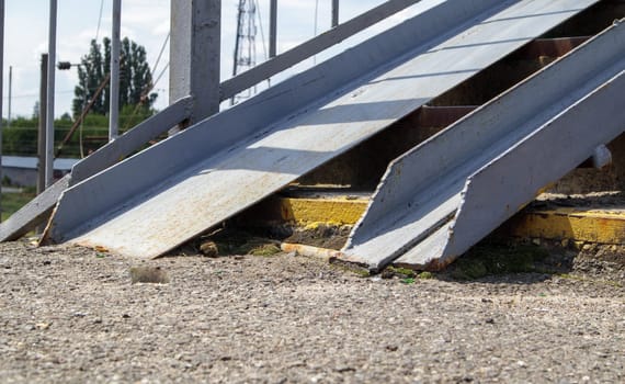 The staircase of the pedestrian crossing with traces of destruction. Two wheelchair rails. Metal railings for bicycles, wheelchairs and strollers with children. Special equipment on the stairs
