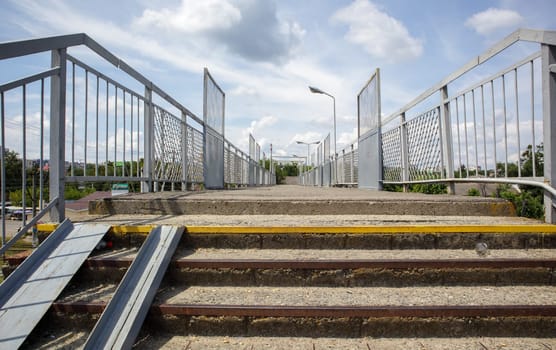 Railway bridge with steps, with impressive steps in perspective. Overhead pedestrian crossing. Bridge stairs connecting one platform to another at the train station