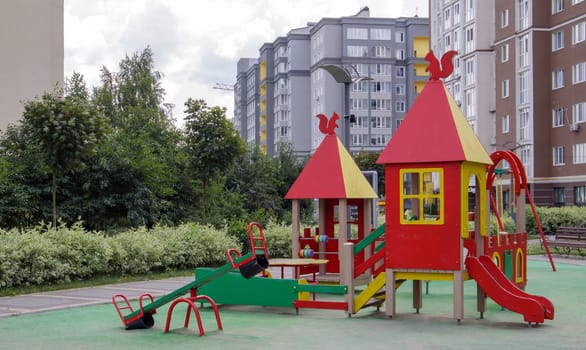An empty modern playground in the courtyard of residential buildings without people and children. Security and protection measures against COVID-19 in the city park. The concept of childhood is over