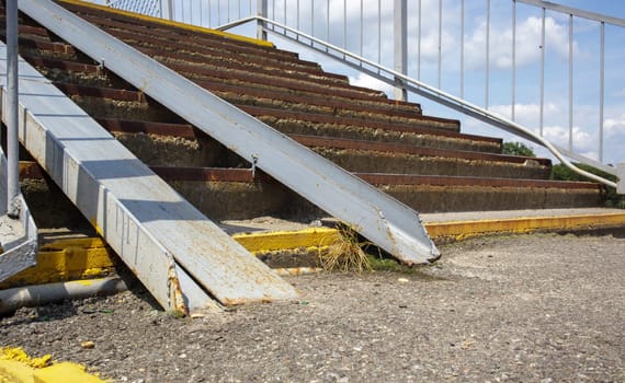 The staircase of the pedestrian crossing with traces of destruction. Two wheelchair rails. Metal railings for bicycles, wheelchairs and strollers with children. Special equipment on the stairs