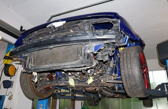 A broken car on a lift in a garage