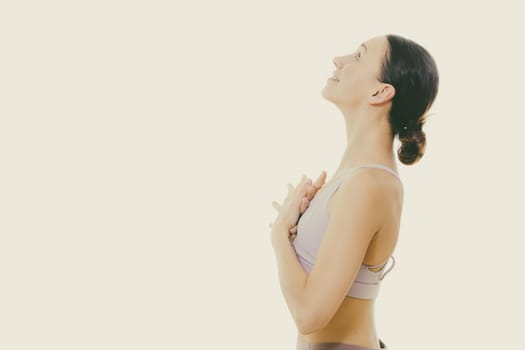 Portrait of gorgeous active sporty young woman practicing breathing exercises in yoga studio. Healthy active lifestyle, working out indoors in gym. Copy space on top.