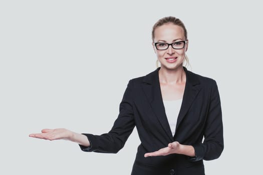 Beautiful young businesswoman smiling, holding open palm with empty copy space. Business woman showing hand sign to side, concept of advertisement product. White background.