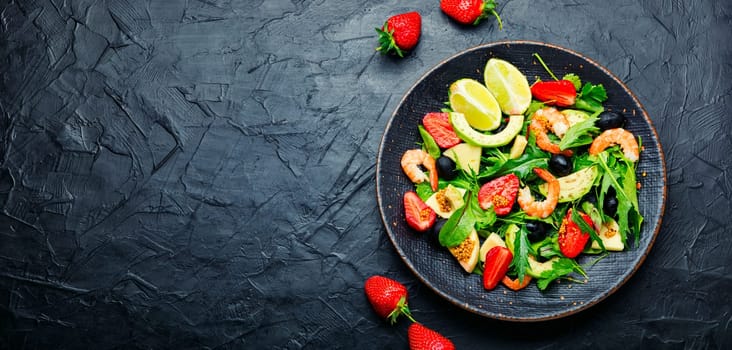Salad with shrimps,strawberries,avocado and herbs.Seafood salad on rustic wooden background.Copy space,space for text