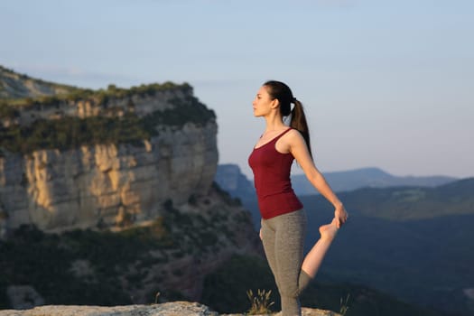 Asian sportswoman stretching leg in the mountain