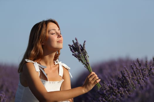 Woman holding bouquet smelling flowers in a lavender field