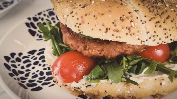 Close-up shot of vegan or plant based hamburger with lettuce tomato and vegenaise in burger bun