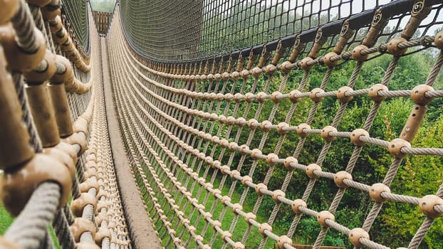 Suspension bridge with rope and mesh nett on a playground for children. Outdoor fun.