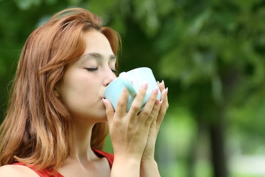 Woman drinking coffee from mug in a park