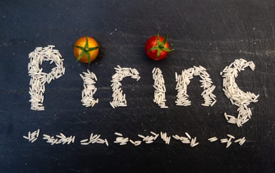 Turkish word pirinç written by white rice grains on a black slate board