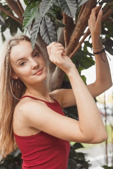 Woman in greenhouse posing at tropical tree.