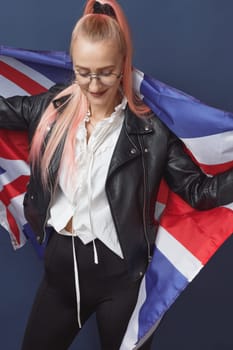 Young woman expat in eyeglasses with great britain flag. Studio shot. English language hipster teacher. Fashionly dressed woman with pink hairs in black leaher jacket and white blouse. Autumn style