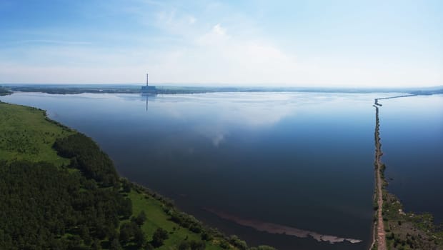 Beryozovskoye reservoir - cooling reservoir of Beryozovskaya GRES. Aerial drone view of lake landscape with road in sunny summer. Berezovskaya GRES is a thermal power plant in the town of Sharypovo, Krasnoyarsk Territory of Russia.