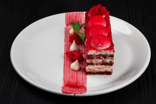 Plate with piece of delicious red velvet cake on black wooden background, food and drink concept