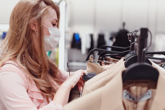 Beautiful female customer wearing protective face mask shopping in clothing store. Diverse People in Fashionable Retail Shop, Choosing Stylish Clothes, Colorful Sustainable Brand Designs