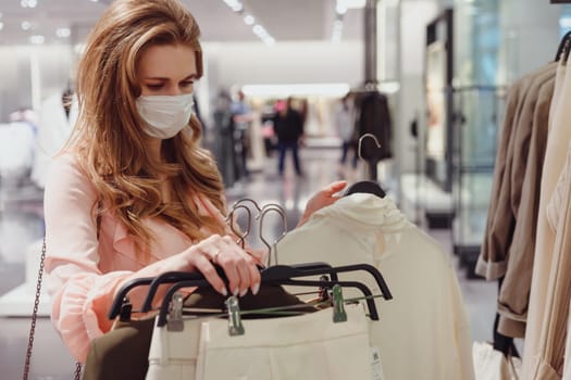 Beautiful female customer wearing protective face mask shopping in clothing store. Diverse People in Fashionable Retail Shop, Choosing Stylish Clothes, Colorful Sustainable Brand Designs