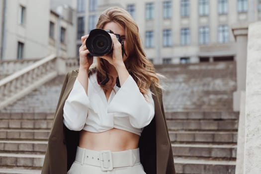 Portrait of woman photographer covering her face with camera outdoors.