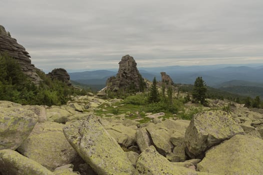 large kurum stones lie in the forest in the mountains, stones covered with moss, against the background of the forest, mountain landscape, high in the mountains..