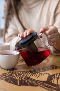 Pour the hot tea into a cup. The cup of tea on the wooden table was illuminated by the soft sunlight that penetrated the warm atmosphere