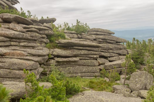 large kurum stones lie in the forest in the mountains, stones covered with moss, against the background of the forest, mountain landscape, high in the mountains..