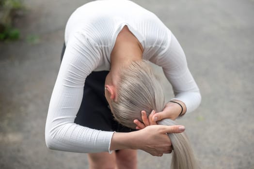 young blond woman making pigtail