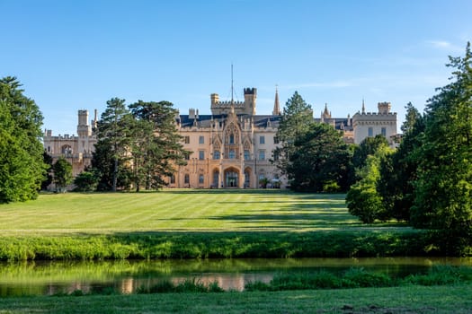 Lednice Chateau with beautiful gardens with flowers and parks on sunny summer day. Lednice-Valtice landmark, South Moravian region. UNESCO World Heritage Site. Czech Republic