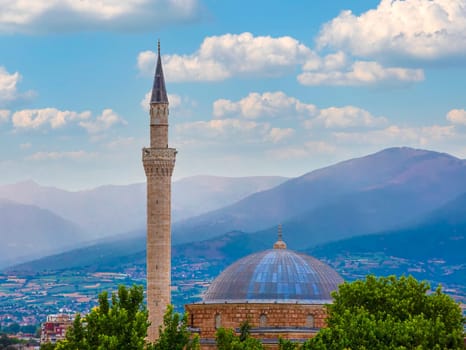 The minaret of the mosque and the trees on the background of the sky. and hills. Selective focus