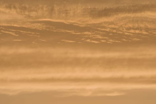 Abstract sky background of deep golden sunset clouds. Full frame color and texture, copy space possible throughout. Rich tones and varied clouds.