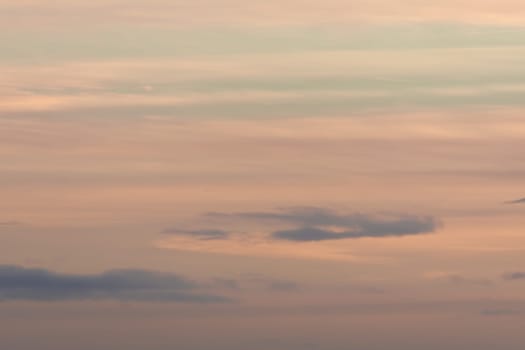 Plain pastel color themed background, made by a sky of gentle clouds at sunset. Mainly orange with some blue, very calm and wispy. Lots of copy space